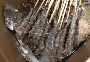 把混合好的一半海盐倒入面包机桶中，然后把串好的虾也摆入面包机中，如果竹有点长可以剪短点，这样子后面面包机的盖子才可以盖得上