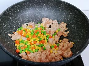 待鸡肉炒至变色后，加入玉米粒，豌豆，胡萝卜丁，小火翻炒，加入一小勺纯净水，中小火煮3-5分钟，将食材煮熟即可。