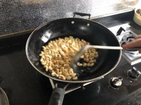 快速倒入腰果。新手的话可以适当调小一点火力。