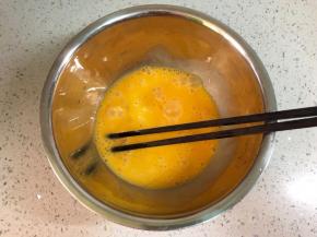 盆里打入两个鸡蛋拌匀。