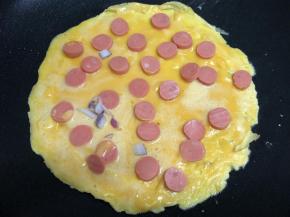 趁鸡蛋糊还没有凝固，铺上火腿片。