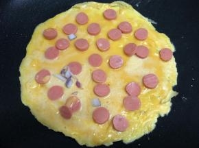 趁鸡蛋糊还没有凝固，铺上火腿片。