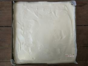 用刮板轻抹表面的蛋糕糊，往烤盘四周推送，使蛋糕糊平整