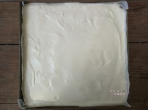 用刮板轻抹表面的蛋糕糊，往烤盘四周推送，使蛋糕糊平整