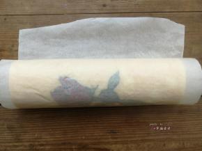 利用擀面杖反卷底部油纸的方式慢慢推送蛋糕片，使蛋糕片自然往前卷起，卷好后油纸包起整条蛋糕卷，底边朝下放置，送入冰箱冷藏1小时定型