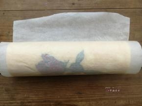 利用擀面杖反卷底部油纸的方式慢慢推送蛋糕片，使蛋糕片自然往前卷起，卷好后油纸包起整条蛋糕卷，底边朝下放置，送入冰箱冷藏1小时定型