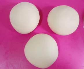 松弛好的面团平均分成三份，滚圆盖保鲜膜。