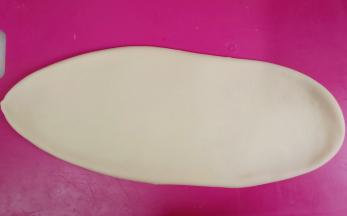 取一个面团分别从中间往上、下擀成舌状。