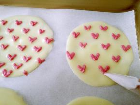 将草莓面糊装入裱花袋，在圆饼上挤出心形。