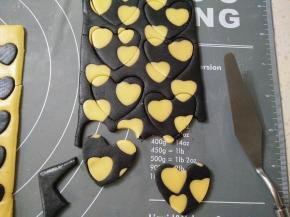 刻出的原色的桃心放在黑饼干胚里，稍微擀一下使桃心和饼干胚平整一致用大一点的心形饼干模刻出形状，用刮板移到烤盘里，剩余的边角再揉成面团做成其它形状。