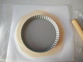 取出面团上面铺一层油纸，用擀面杖先按压几次，再慢慢擀开，将面团擀的与模具大一圈。