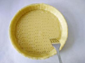 撕掉油纸，手拖起面皮倒扣在模具上，用手轻轻按压使面皮紧贴模具，切去多余边，用叉子在面团底部戳洞，松弛20分钟（否则烤焙的时候塔皮会回缩），里面铺一层油纸，再放上烘焙重石或者豆子。