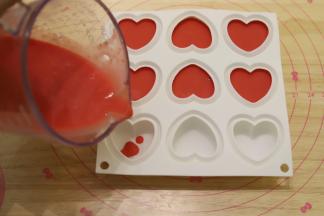 准备一个六连的爱心硅胶模，将草莓慕斯液倒入模具内，冰箱冷冻4小时左右。
