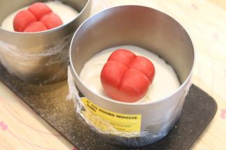 开始组装爱巢蛋糕：冰箱中取出慕斯圈，倒入一点酸奶慕斯液，将两个爱心草莓慕斯放在中间。