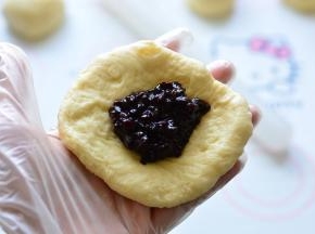 把面团擀成圆形，包入紫米饭，底部收口揉圆