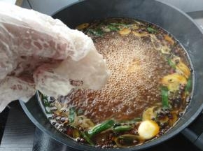 转中小火，把鱼片摊开一片片下入锅内。