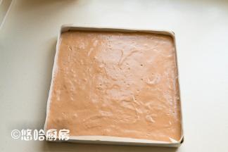 拌匀的面糊倒回余下的蛋白霜中继续翻拌均匀，倒入已铺好油布的烤盘中，烤盘在台面上轻震几下，震出面糊中的大气泡。