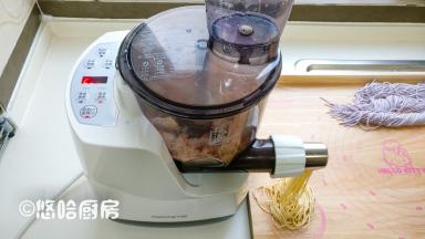 紫色面条压好后，面条机自动停止，再次重复上面的步骤，蔬菜汁换成了胡萝卜汁，很快就出来黄色面条。