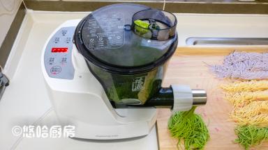 最后继续放面粉，蔬菜汁是菠菜汁，很快压出绿色的面条，压好的面条卷起后摆放在案板一边。