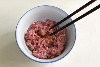 往搅好的肉馅中加入姜末、生抽、料酒和盐，用筷子顺着一个方向搅拌上劲。