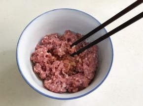 往搅好的肉馅中加入姜末、生抽、料酒和盐，用筷子顺着一个方向搅拌上劲。