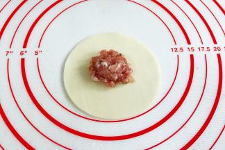 取一张饺子皮，中间放入适量的肉馅。