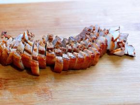 炸好的五花肉浸泡冷水中降温，再切薄片备用。