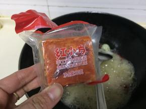 放入红小方火锅底料继续翻炒