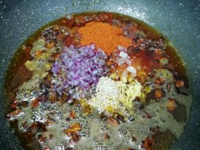 放入白芝麻、辣椒粉、冰糖碎、洋葱碎末和生姜碎末，转小火炒至辣椒出红油。