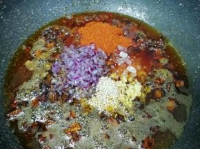 放入白芝麻、辣椒粉、冰糖碎、洋葱碎末和生姜碎末，转小火炒至辣椒出红油。