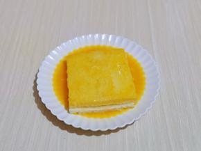 放入打散的蛋液盘中，将吐司的两面及四边均匀裹上蛋液。