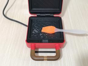 三明治机器连接电源，将上下的烤盘刷上少许食用油。