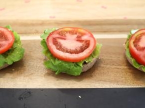 生菜洗净擦干，番茄切成薄片，依次放在汉堡胚上面。