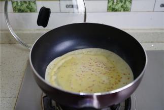 因为面糊里有加入了玉米油，这样子在烙饼的时候就不用再刷油了，用汤勺盛一勺面粉在锅里，然后摊均开。