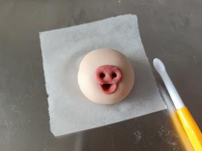 红色面团借助旁边的工具做出猪猪的鼻子嘴巴来