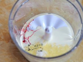 绞肉机里装好打蛋器配件，倒入淡奶油，加入糖粉和红色色素。