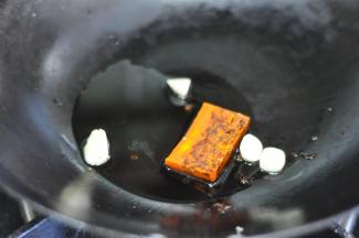 锅里倒少许油，放入火锅底料和蒜粒。