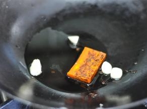 锅里倒少许油，放入火锅底料和蒜粒。