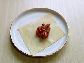 取一张大馄饨皮，放入馅料，将皮四周涂抹上水，有助于粘合。