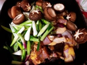 把鲜冬菇和葱蒜也加入到调好味的鸡块中拌匀。
