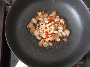 小火煎至出油，有点焦黄。然后放入辣椒和蒜头，煸出香味。