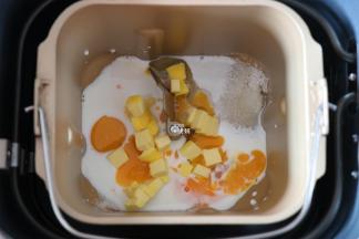 将全蛋液、牛奶倒入面包机的面包桶中，盐、糖对角放，放一半的黄油（30g）；