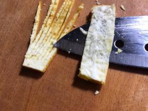 再把果皮切两片一指长宽的条，去除内膜，再切成丝不切断，如图