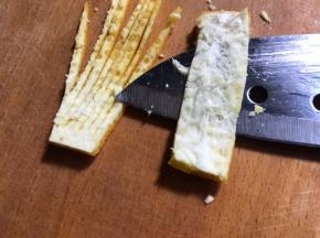 再把果皮切两片一指长宽的条，去除内膜，再切成丝不切断，如图
