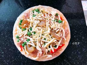 铺上辣椒，火腿，鲜虾，青豆，再撒上一些芝士碎