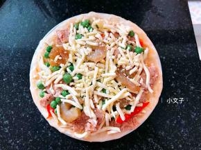 铺上辣椒，火腿，鲜虾，青豆，再撒上一些芝士碎