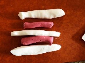 准备做大理石纹的汤圆，红白面团按图分割成长条。纽在一起搓成长条