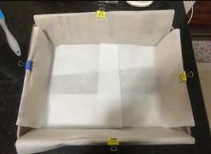 准备蛋糕烤盘，找个纸箱子，剪出几个可以放进烤盘四边的纸片，纸板高出一部分，里面铺油纸，油纸光面在外，毛面在内侧不然影响蛋糕爬升，加入硬纸板的作用是，一部分辅助蛋糕糊量多长高，主要是防止四周边缘上色，符合古早味的外形。