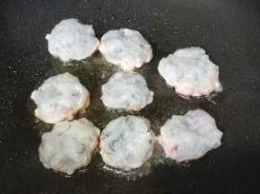手湿水，将虾泥捏成圆饼形，放入不粘锅里