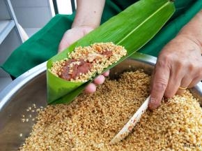 顶部折一个漏斗的样子，铺一层糯米，中间加猪肉馅，再铺米盖住馅料，包之前稍微抖一抖，把周围多余的糯米抖掉。